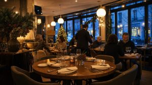 Salle de restaurant française chaleureuse et élégante ouverte le jour de Noël, avec tables dressées, lumière ambrée et décorations hivernales discrètes.