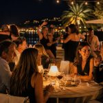 Terrasse de restaurant dansant à Toulon en soirée, avec des convives attablés et des couples qui dansent face au port illuminé.